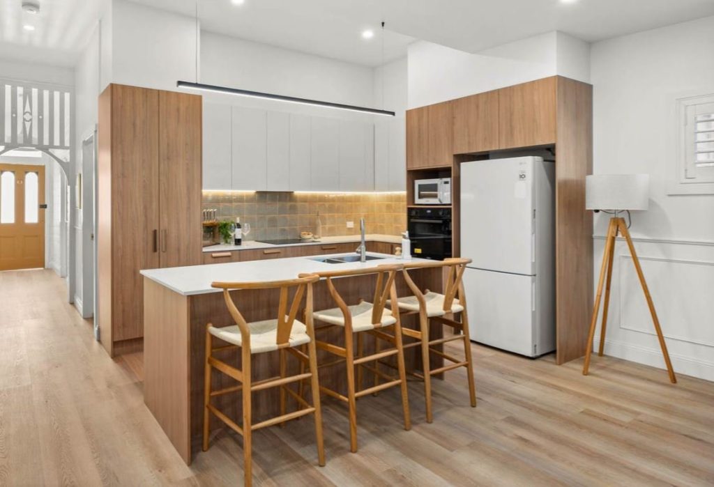 Cottage kitchen in Mayfield with white overhead cabinets, Tasmanian Oak base cabinetry and stone island benchtop